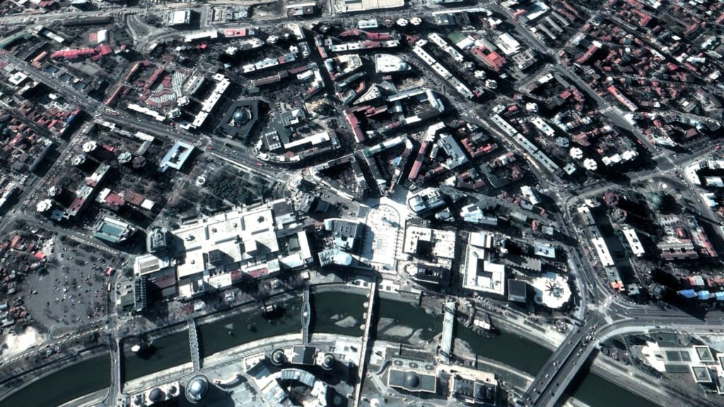 High-angle aerial view of an urban area with detailed 3D rendering of buildings and roadways, highlighting the complexity of city infrastructures.